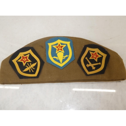 163 - A USSR military cap with a large collection of assorted badges.