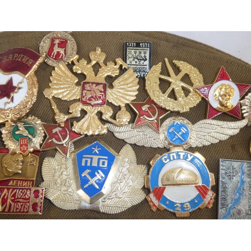 163 - A USSR military cap with a large collection of assorted badges.