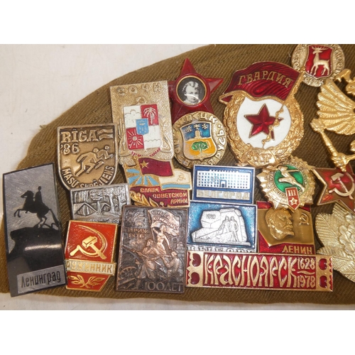 163 - A USSR military cap with a large collection of assorted badges.