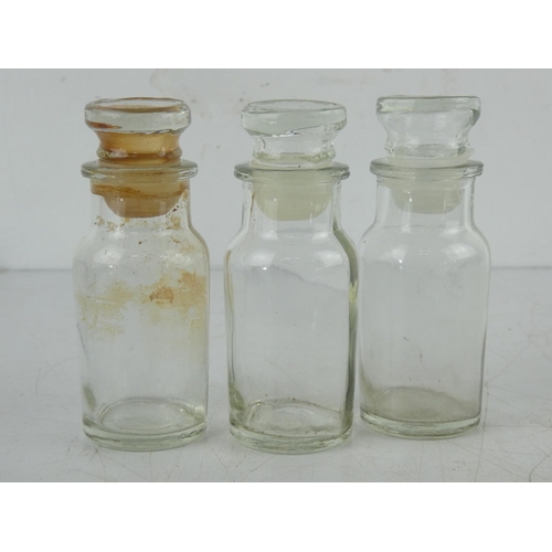 12 - Three clear glass chemist bottles.