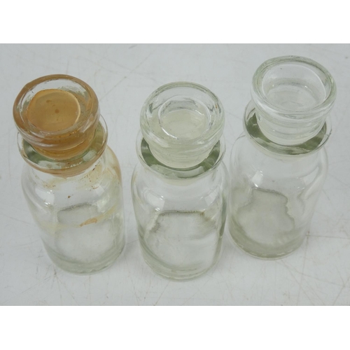 12 - Three clear glass chemist bottles.