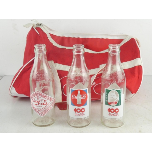 130 - Three vintage Coca Cola bottles and a Coca Cola sports bag.