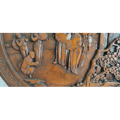 451 - A highly carved circular wall hanging of an oriental scene.