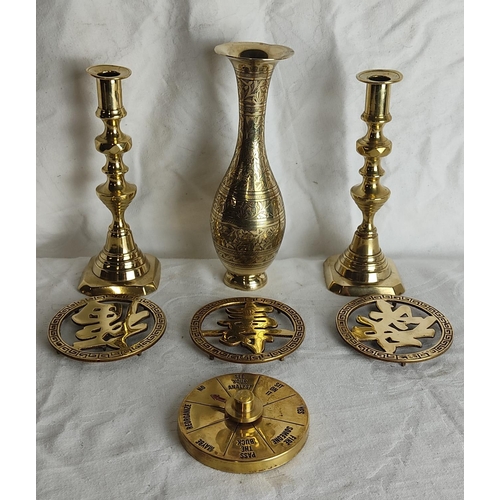 88 - A pair of vintage brass candlesticks, a decorative brass vase, three brass trivets and more.