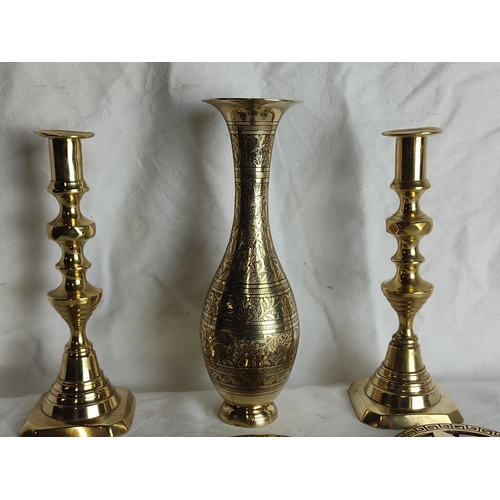 88 - A pair of vintage brass candlesticks, a decorative brass vase, three brass trivets and more.