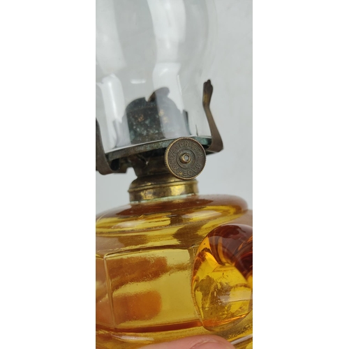 14 - An antique oil lamp with amber glass base.