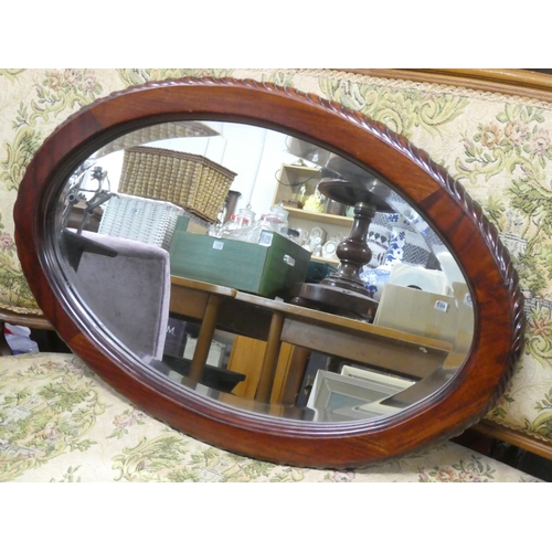 473 - A mahogany framed oval wall mirror. 74x48cm.