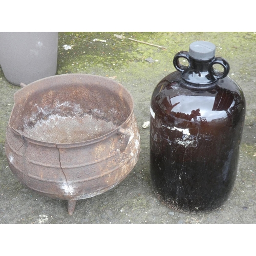 522 - An antique three legged pot (a/f) and a vintage coloured glass demi john bottle.