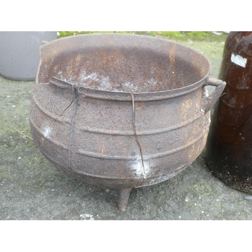 522 - An antique three legged pot (a/f) and a vintage coloured glass demi john bottle.