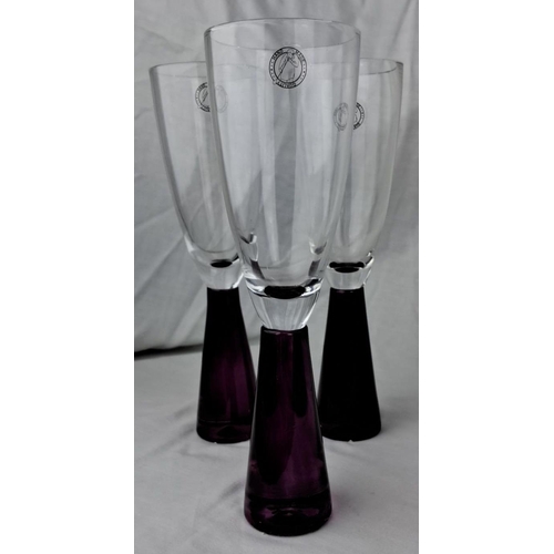 114 - Set of three clear glass goblets with purple stems and badge logo detailing.