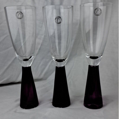 114 - Set of three clear glass goblets with purple stems and badge logo detailing.