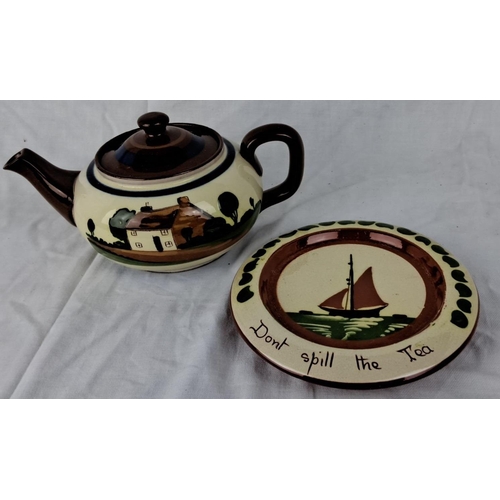 117 - Watcombe Torquay Pottery teapot and trivet set, hand-painted cottage and sailboat design, marked 