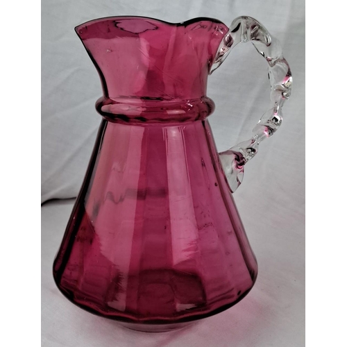 137 - Vintage cranberry glass pitcher with a clear twisted handle. The pitcher has a fluted mouth and a bu... 