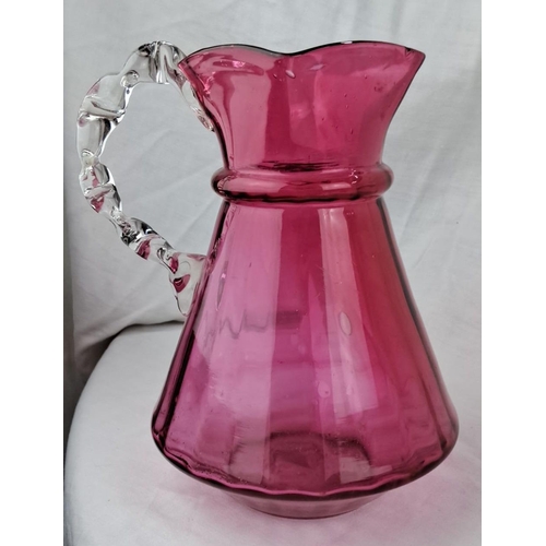 137 - Vintage cranberry glass pitcher with a clear twisted handle. The pitcher has a fluted mouth and a bu... 