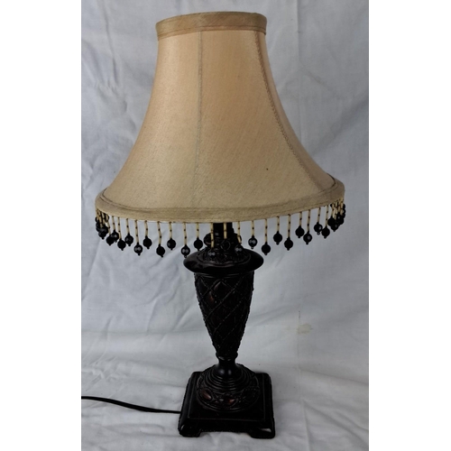 27 - Antique-style table lamp with beige fabric shade and black beaded fringe. The lamp features an ornat... 