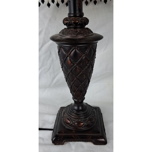 27 - Antique-style table lamp with beige fabric shade and black beaded fringe. The lamp features an ornat... 