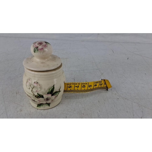 572 - Small ceramic tape measure with hand-painted floral designs.