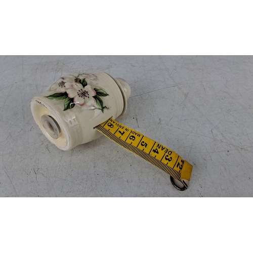 572 - Small ceramic tape measure with hand-painted floral designs.