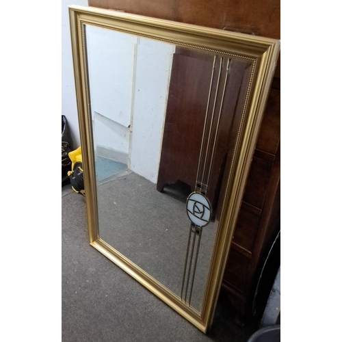 580 - Rectangular gilt-framed mirror with bevelled edges, featuring gold line details and a decorative cen... 