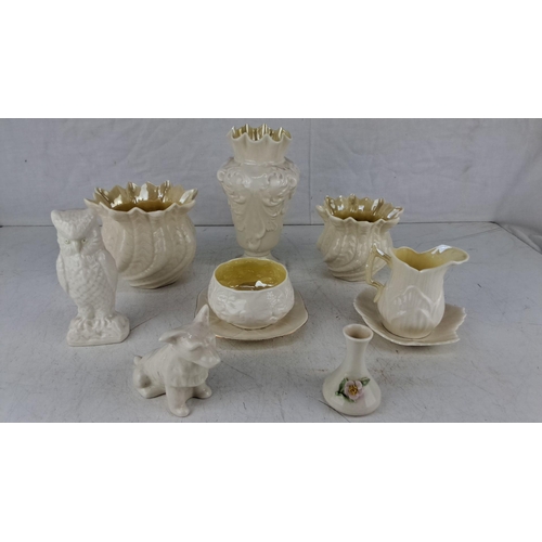 614 - Collection of 8 Belleek pottery items includes owl and dog figurines, a pitcher with a plate, vases,... 