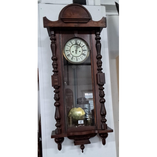 67 - An antique Gustav Becker wall clock featuring a glass front and intricate wood turned spindles. The ... 