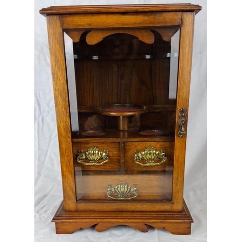 72 - An antique oak smoker's cabinet with a glass door and three brass-handled drawers. Interior shelves ... 