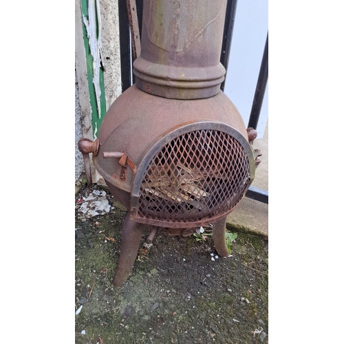 664 - Antique cast iron patio heater/stove with ornate detailing and mesh door. Features a tall chimney an... 