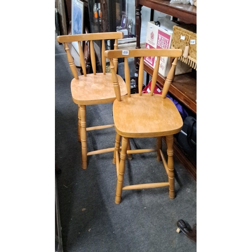 1221 - Pair of wooden bar stools with spindle backrests and turned legs, featuring a natural light wood fin... 