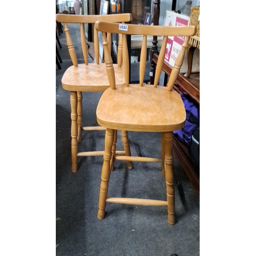 1221 - Pair of wooden bar stools with spindle backrests and turned legs, featuring a natural light wood fin... 