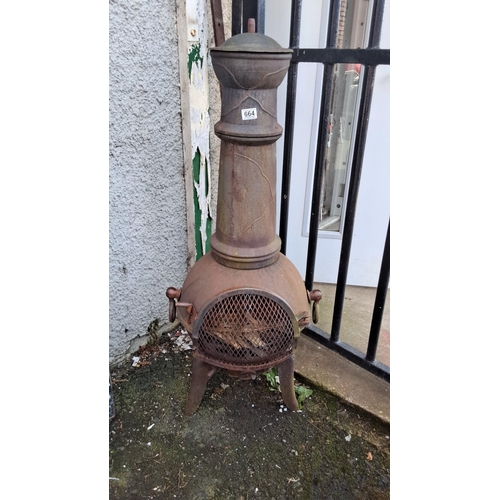 664 - Antique cast iron patio heater/stove with ornate detailing and mesh door. Features a tall chimney an... 