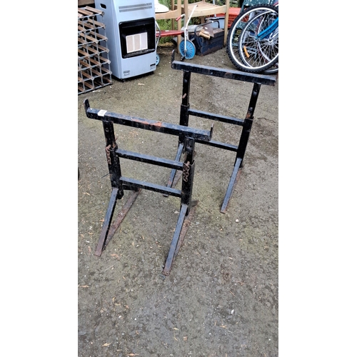 671 - Pair of sturdy black metal sawhorses with chain supports. Simple and functional design.