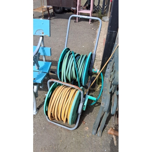 679 - Pair of garden hose reels. Includes two plastic and metal reel carts, one with green and the other w... 