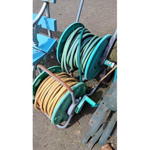 679 - Pair of garden hose reels. Includes two plastic and metal reel carts, one with green and the other w... 