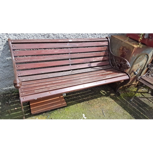 686 - Wooden garden bench with cast iron sides featuring intricate designs and lion head motifs.