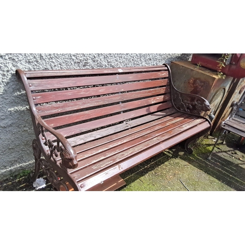 686 - Wooden garden bench with cast iron sides featuring intricate designs and lion head motifs.