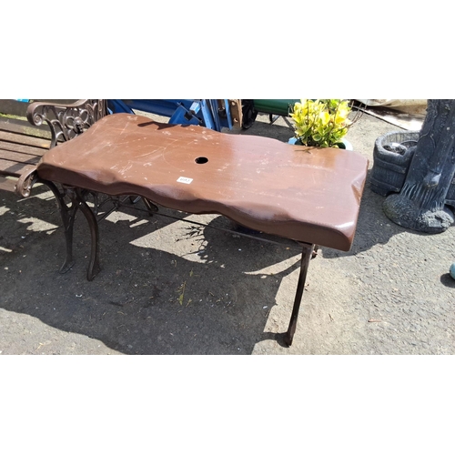 693 - Cast iron garden table with a wooden slab top, featuring a natural edge design with a central hole.