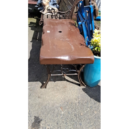 693 - Cast iron garden table with a wooden slab top, featuring a natural edge design with a central hole.