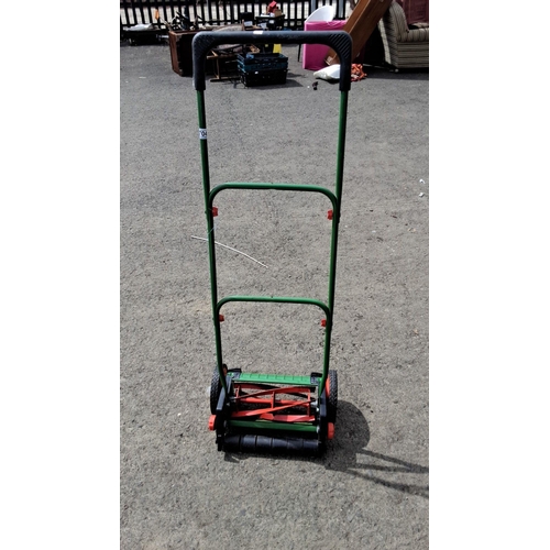 704 - Manual push lawn mower with a green metal frame and dual black wheels. Equipped with red reel blades... 