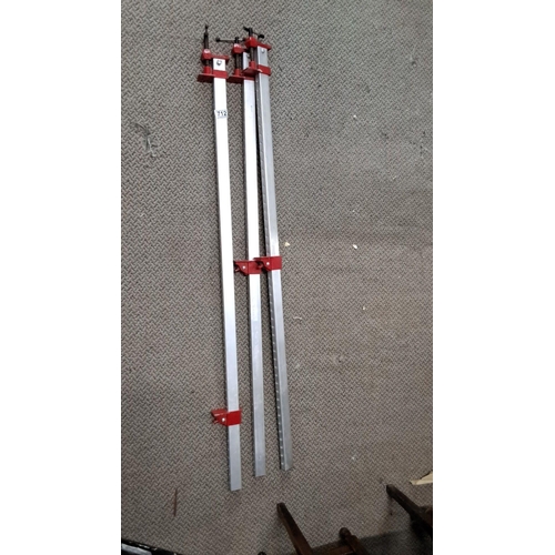 712 - Three metal bar clamps with red screw mechanisms.