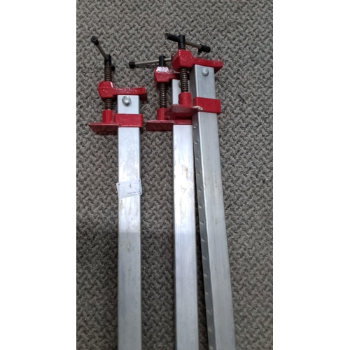 712 - Three metal bar clamps with red screw mechanisms.