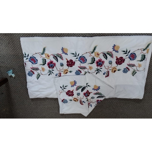 782 - Set of embroidered bed linens with vibrant floral motifs on white fabric. The set includes a larger ... 