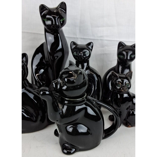 12 - A collection of black ceramic cat figurines. The figurines showcase intricate detailing with green e... 