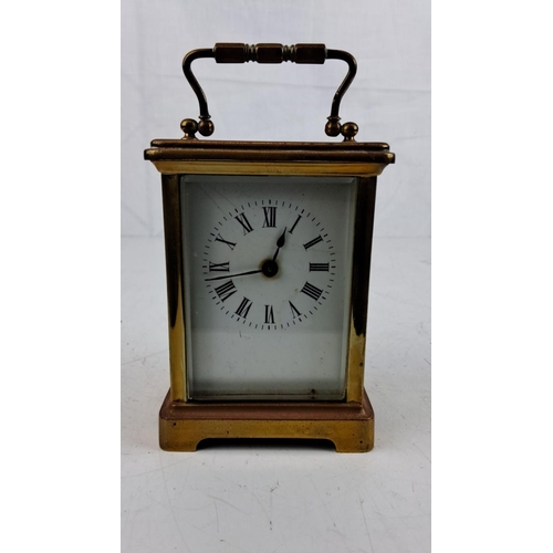 15 - An antique Brass carriage clock with Roman numeral dial and beveled glass panels, featuring a classi... 