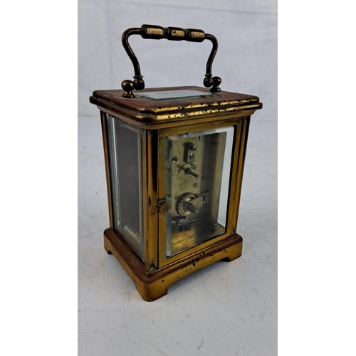 15 - An antique Brass carriage clock with Roman numeral dial and beveled glass panels, featuring a classi... 