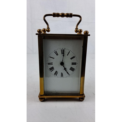 16 - Antique brass carriage clock with Roman numeral dial, glass panels, and intricate handle detailing, ... 