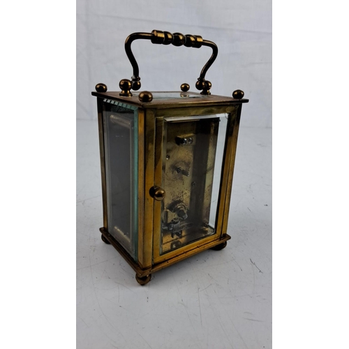 16 - Antique brass carriage clock with Roman numeral dial, glass panels, and intricate handle detailing, ... 