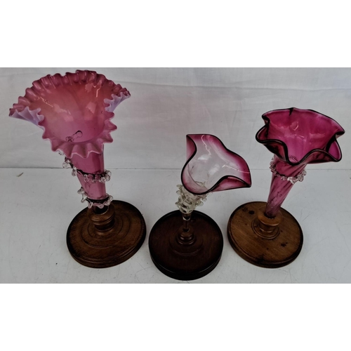 27 - Set of three Victorian cranberry glass epergnes. They have fluted and ruffled edges, adorned with an... 