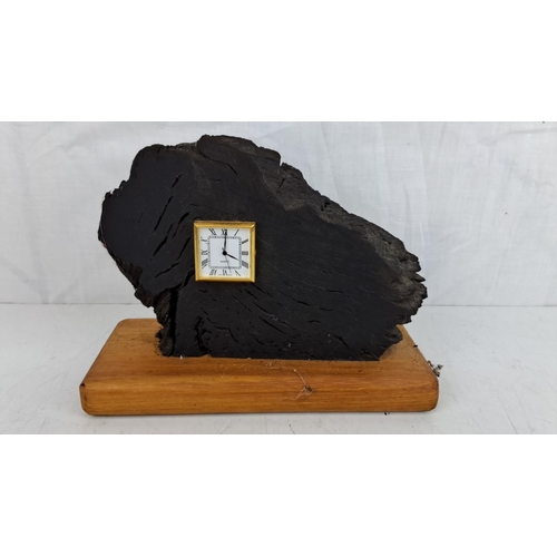 32 - Unique miniature quartz clock embedded in bog oak with a gold-trimmed face. Mounted on a wooden base... 