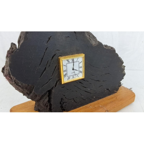 32 - Unique miniature quartz clock embedded in bog oak with a gold-trimmed face. Mounted on a wooden base... 