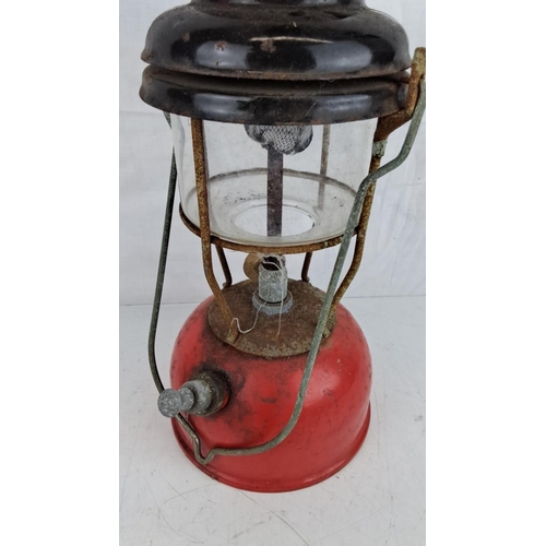 33 - Vintage red and black kerosene lantern with metal frame and glass chimney, showing a rustic, weather... 